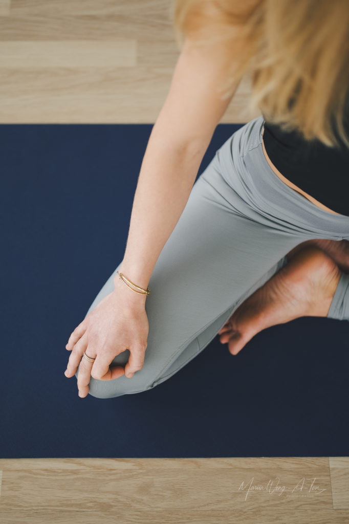 A woman dressed in a black Pilates outfit performing an exercise on a Pilates reformer